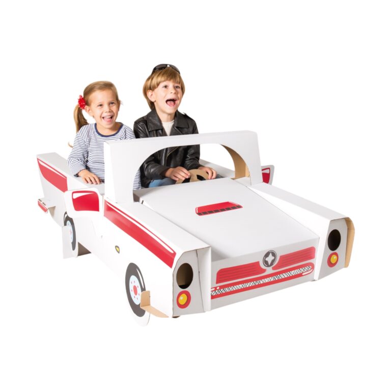 Deux enfants heureux jouent dans une voiture cabriolet vintage en carton blanc et rouge. Jouet créatif pour enfant.