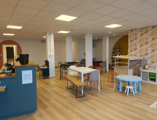 Espace café ludique avec tables modernes, coin jeux pour enfants et décoration chaleureuse au style scandinave.