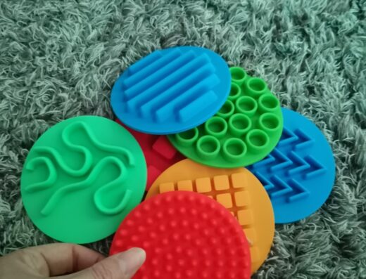 Disques sensoriels tactiles colorés pour l'éveil des enfants et la motricité fine sur un tapis texturé.