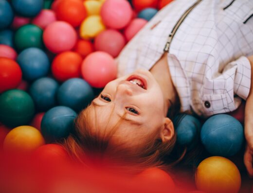 Enfant souriant allongé dans une piscine à boules colorées