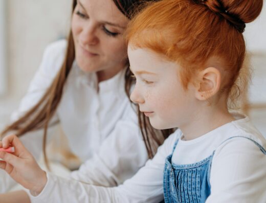 Une enseignante aide une petite fille rousse à faire ses devoirs de lecture et d'écriture à l'école.