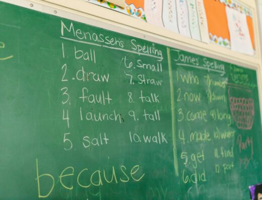 Liste de mots de dictée écrits à la craie sur un tableau vert d'école primaire.